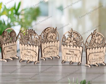 May include: Five wooden flower pot decorations with the text "Happy Mother's Day" on each. The pots are decorated with different floral designs.