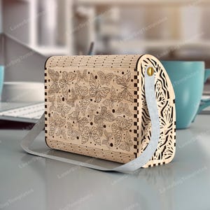 May include: A wooden box with a hinged lid and a metal handle. The box is decorated with a laser-cut design of butterflies. The box is a light brown color.
