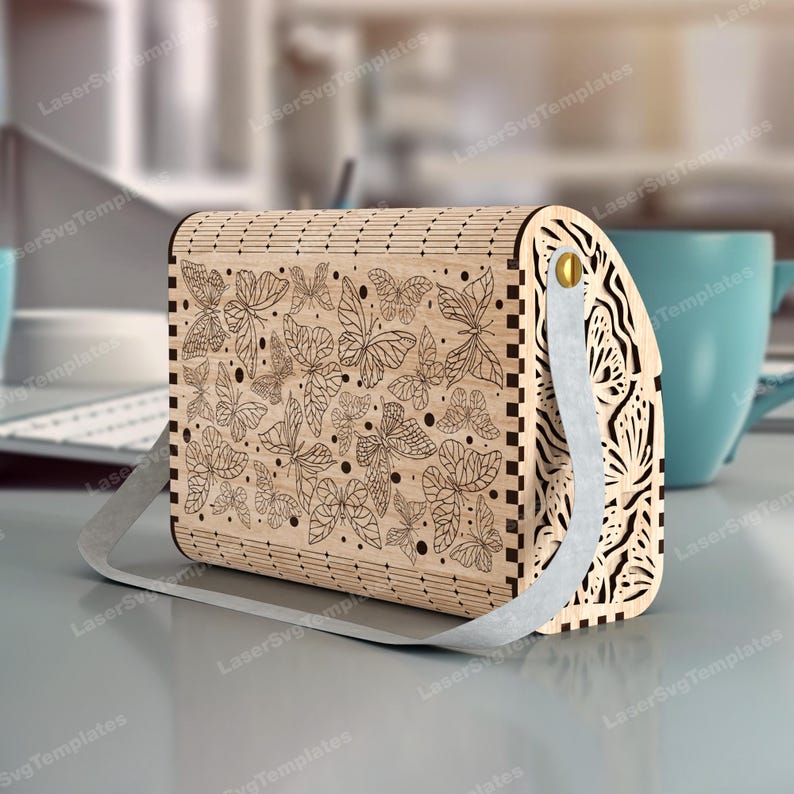 May include: A wooden box with a hinged lid and a metal handle. The box is decorated with a laser-cut design of butterflies. The box is a light brown color.