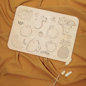 Peut inclure: Un puzzle en bois représentant différents fruits et baies, dont une pastèque, un citron, une pomme, une poire, des raisins, un ananas, une grenade et des cerises. Les pièces du puzzle sont découpées en forme de fruits et de baies.