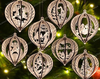 May include: A collection of laser-cut wooden Christmas ornaments. Each ornament features a unique Nativity scene or holiday design, including angels, a Christmas tree, and the text "Holy Night". The ornaments are suspended against a blurred green background.