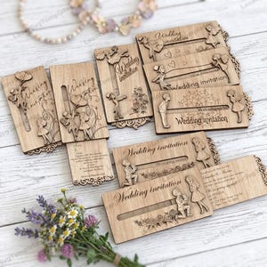 May include: A collection of laser-cut wooden wedding invitations. Each invitation features intricate designs of couples, flowers, and decorative borders. The words "Wedding invitation" are engraved on the front of each card. Some cards have additional text.