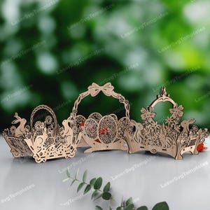 May include: Three laser-cut wooden Easter basket decorations. Each basket features intricate designs of flowers, bunnies, and eggs. The baskets are made of light-colored wood and are suitable for Easter decor.