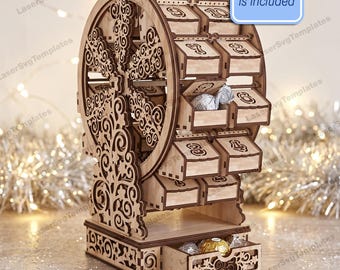 May include: A laser-cut wooden ferris wheel advent calendar with numbered compartments for small treats. The structure features intricate scrollwork on the sides and a base drawer. A blue rectangular label states, Instruction is included.