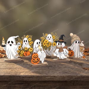May include: A collection of six wooden ghost figurines featuring various designs, including ghosts holding a candle, pumpkins, yellow flowers, a book with the text Stay Spooky, and a coffee cup, all mounted on individual oval wooden bases.