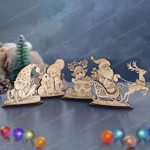 Op de afbeelding: Houten kerstversieringen. De afbeelding toont een kabouter op een slee, een sneeuwpop met een rendier, een rendier in een zak met cadeaus en de kerstman in een slee getrokken door een rendier. De uitsparingen zijn gemaakt van lichtbruin hout.