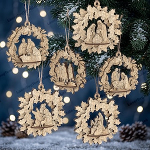 May include: Five circular light brown wooden Christmas ornaments featuring intricate laser-cut nativity scenes framed by detailed holly leaf and berry wreaths. Each ornament hangs from a thin twine loop, displaying unique religious figures.