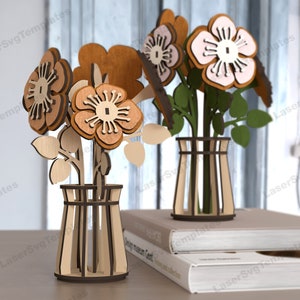 May include: Two wooden vases with flowers. The vase on the left has a brown and white floral design. The vase on the right has a pink and white floral design. Both vases are on a stack of books.