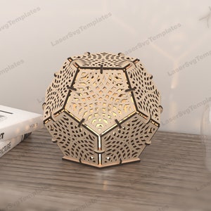 May include: A wooden geometric lampshade with a intricate laser cut design. The lampshade is a light brown color and has a hexagonal shape.