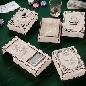 Könnte beinhalten: Holz-Spielkartenboxen mit lasergeschnittenen Designs. Die Boxen zeigen Spielkartensymbole, darunter Pik, Kreuz und Herz. Eine Box ist geöffnet und zeigt ein Kartenspiel. Die Boxen befinden sich auf einer grünen Oberfläche.