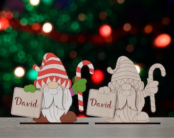 May include: Two wooden Christmas gnomes holding signs with the name "David" on them. The gnomes are wearing red and white striped hats and have white beards. They are holding candy canes in their hands.