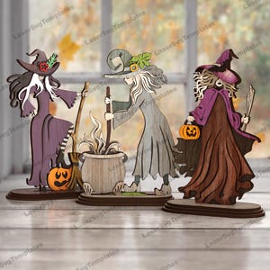 May include: Wooden Halloween decorations depicting three witches. One holds a broom and pumpkin, another stirs a cauldron, and the third carries a pumpkin. The decorations are on wooden bases, suitable for seasonal display.