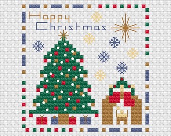 May include: A cross-stitch pattern on white fabric featuring a green Christmas tree with red and gold ornaments, a small brown house, and blue and gold snowflakes. The text Happy Christmas is stitched in blue, framed by a colorful checkered border.