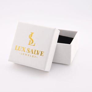 May include: White jewellery box with a gold logo that says "LUX SALVE JEWELLERY".