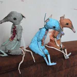 May include: Three handmade plush rat toys, each with a different colored fur: gray, blue, and brown. They are sitting on a brown couch with their long tails trailing behind them. The caption reads "Grunge rats by RatBerry".