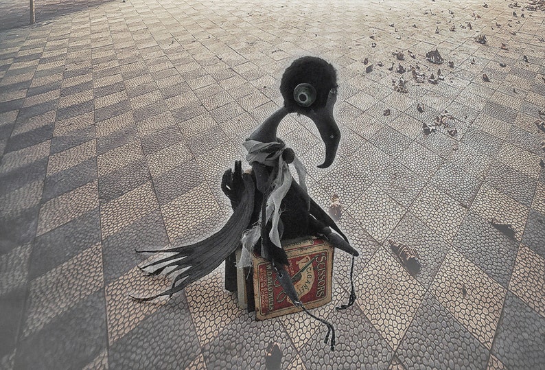 K&ouml;nnte beinhalten: Eine schwarze, kr&auml;henartige Figur mit langem Hals und Schnabel sitzt auf einer Schachtel Streichh&ouml;lzer. Die Schachtel ist rot und wei&szlig; mit dem Wort "Schere" darauf gedruckt. Die Figur sitzt auf einem Schachbrettmusterboden.