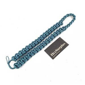K&ouml;nnte beinhalten: Ein teal-farbenes Paracord-Lanyard mit geflochtenem Design. Das Lanyard ist an einem Ende geschlauft und hat am anderen Ende eine kleine Schlaufe. Ein schwarzes rechteckiges Etikett mit dem Text "HtxSurplus" befindet sich neben dem Lanyard.