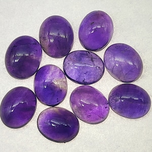 May include: Ten oval-shaped amethyst gemstones in various shades of purple. The stones are smooth and polished, with a slight sheen.