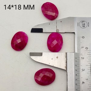 May include: Four faceted, oval-shaped, hot pink gemstones, each approximately 0.55 x 0.71 inches, are displayed. A metal caliper is used to measure the stones. The text "14*18 MM" is visible in the upper left corner.