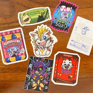 May include: A collection of ten colorful stickers featuring various cartoon characters and designs. The stickers include a blue and white squid, a yellow and white creature, a red and white creature, a blue and white creature, a red and white creature, a blue and white creature, a red and white creature, a blue and white creature, a red and white creature, and a blue and white creature. The stickers are all on a wooden surface.