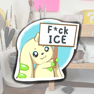 Peut inclure: Un autocollant représentant un personnage de dessin animé tenant une pancarte avec l'inscription "F*ck ICE". Le personnage est jaune clair avec des détails verts et de grands yeux bleus. Le fond est bleu clair.