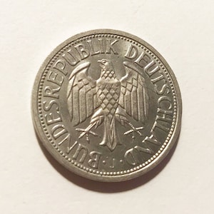 May include: A silver German coin with the words "Bundesrepublik Deutschland" around the edge and a stylized eagle in the center.