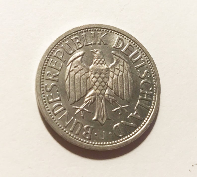 May include: A silver German coin with the words "Bundesrepublik Deutschland" around the edge and a stylized eagle in the center.