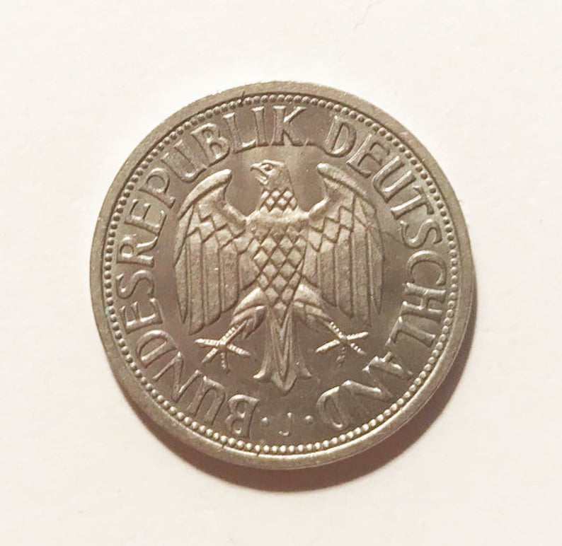 May include: A silver German coin with the text "Bundesrepublik Deutschland" and a stylized eagle in the center.