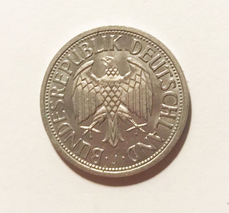 May include: A silver German coin with the words "Bundesrepublik Deutschland" around the edge and a stylized eagle in the center.
