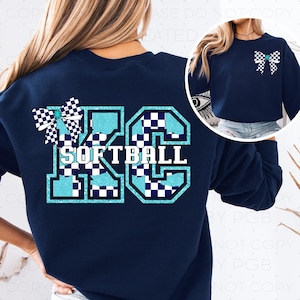 Op de afbeelding: Marineblauw sweatshirt met een groot "KC SOFTBALL" ontwerp op de rug. Het ontwerp heeft een geblokte strik, teal accenten en een wit en teal kleurenschema. Een kleinere versie van de strik staat op de voorkant.