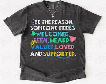 Könnte beinhalten: Dunkelgraues T-Shirt mit dem Text "BE THE REASON SOMEONE FEELS WELCOMED, SEEN, HEARD, VALUED, LOVED, AND SUPPORTED." Der Text ist in verschiedenen Farben und Schriftarten, mit einem Herz und einer Blume.