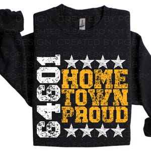 Pu&ograve; includere: Felpa nera con la scritta "64901 Home Town Proud" in bianco e oro. Il design include cinque stelle bianche sopra e sotto il testo. La felpa &egrave; del marchio Gildan.