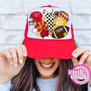 May include: Red, white and yellow trucker hat with a football, stars and flowers design. The hat has a mesh back and a white front panel with the text "KC".