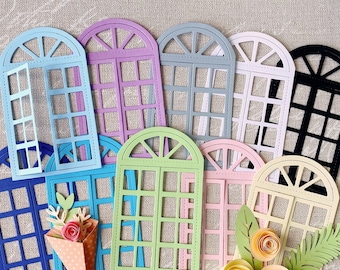 Puede incluir: Un conjunto de diez formas de ventanas troqueladas en varios colores, incluidos azul, verde, rosa, morado y negro. Las ventanas son todas arqueadas y tienen un patrón de cuadrícula. Algunas de las ventanas tienen flores u hojas adheridas a ellas.