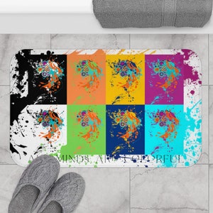 Peut inclure: Un tapis de bain coloré avec un motif répété d'un visage stylisé entouré de cercles colorés. Le texte "All Minds Are Colorful" est imprimé en bas du tapis.