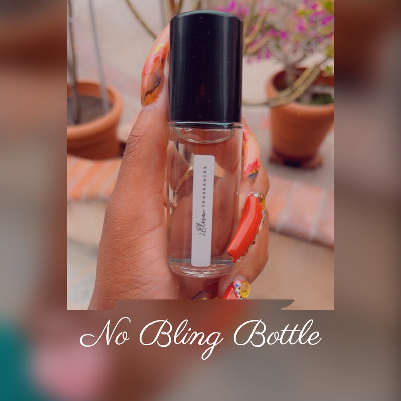 K&ouml;nnte beinhalten: Eine transparente Glas-Rollflasche mit schwarzem Verschluss und einem wei&szlig;en Etikett mit der Aufschrift "Elara Fragrances". Die Flasche wird von einer Hand mit rotem und orangefarbenem Nagellack gehalten.