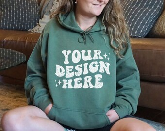 May include: A green hooded sweatshirt with the text "YOUR DESIGN HERE" in white lettering. The sweatshirt has a distressed, vintage look.