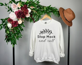 May include: White sweatshirt with black text that reads "Stop Mock and roll" with a small leaf design above the text.