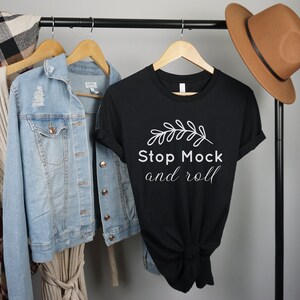 May include: Black t-shirt with white text that reads "Stop Mock and roll" with a small white leaf design above the text.
