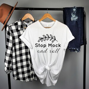 May include: White t-shirt with a black graphic that says "Stop Mock and roll" with a small leaf design above the text.