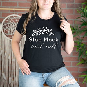 May include: A black t-shirt with a white graphic design featuring a leafy branch and the text "Stop Mock and roll".