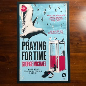 May include: A poster with a black border featuring a large white seagull and the text "PRAYING FOR TIME" by George Michael. The poster has a blue background with flying seagulls and a red phone booth.