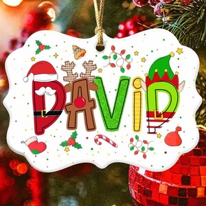May include: White ceramic Christmas ornament with the name "DAVID" spelled out in colorful letters. The letters are decorated with Santa, reindeer, elf, and other Christmas imagery.