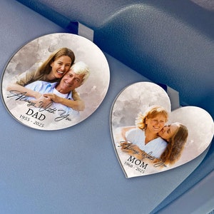 May include: Two heart-shaped car air fresheners with photos of a couple. The top one says "Always With You DAD 1955-2023". The bottom one says "Always With You MOM 1960-2023".