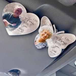 May include: Two car air fresheners with watercolor backgrounds. One is a heart shape with a photo of a man and the text "I am always with you. Dad 1952-2025". The other is a butterfly shape with a photo of a woman and the text "I am always with you. Mom 1943-2024".
