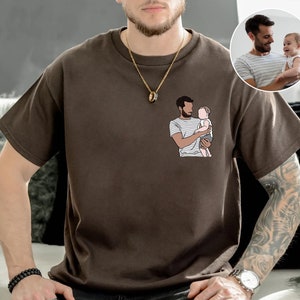May include: A brown t-shirt with a graphic of a person holding a child. The graphic is a line drawing in black and white.