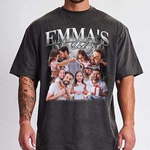 May include: A black t-shirt with a faded look featuring a collage of photos of a family. The text "EMMA'S Dad" is printed in white on the shirt.