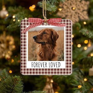 May include: A square hanging ornament featuring a brown and white gingham border and a central photograph of a golden-colored dog. The ornament includes a white bottom section with the black text FOREVER LOVED and a red and white gingham ribbon bow.