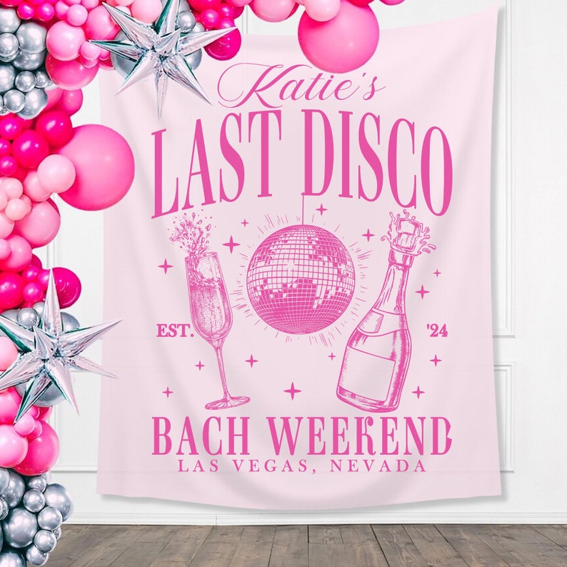 May include: Pink bachelorette party backdrop with the text "Katie's Last Disco" and "Bach Weekend Las Vegas, Nevada". The backdrop also features a champagne glass, a bottle of champagne, and a disco ball.