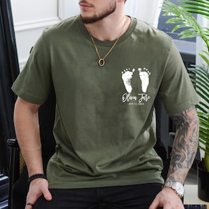 May include: A green t-shirt with white baby footprints and the text "Olivia Jane" and "APR 11, 2024".